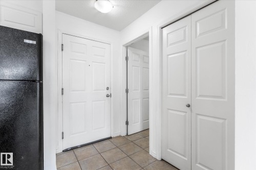 Tiled flooring, paneled interior doors, flush-mount ceiling light fixture, and black finish refrigerator - #109 4309 33 St, Stony Plain, AB 