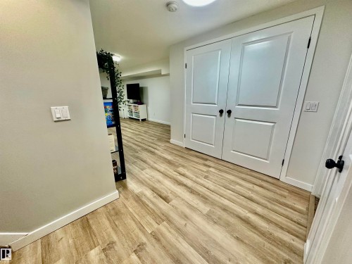 Wood-finish flooring, double-panel interior doors with matte black hardware, and neutral wall tones - 4723 105 Street Nw, Edmonton, AB 