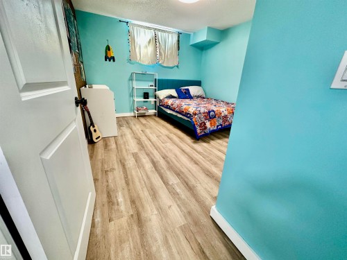 Interior room featuring wood-finish flooring, a recessed window, and a white two-panel interior door - 4723 105 Street Nw, Edmonton, AB 