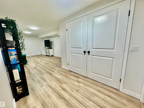 Wide-plank wood-finish flooring, white double doors with matte black hardware, and neutral wall tones - 4723 105 Street Nw, Edmonton, AB 
