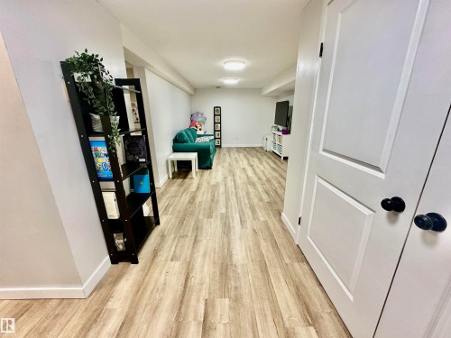 Interior space featuring wood-finish flooring, white walls, dual-panel interior doors with matte black hardware, and flush-mount ceiling lighting - 4723 105 Street Nw, Edmonton, AB 