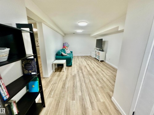 Open interior space featuring light-toned wood-finish flooring, neutral walls, and dual flush-mount ceiling lighting - 4723 105 Street Nw, Edmonton, AB 