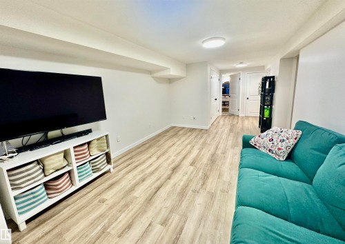 Neutral-toned interior space featuring wood-finish flooring, white walls, flush-mount ceiling lighting, and multiple panel doors - 4723 105 Street Nw, Edmonton, AB 