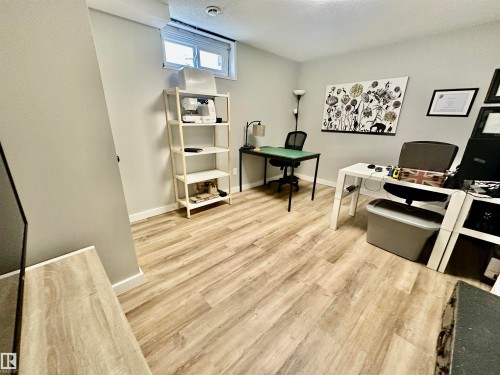 Room featuring wood-finish flooring, neutral wall paint, and a horizontal egress-style window - 4723 105 Street Nw, Edmonton, AB 