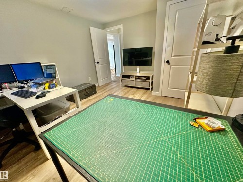 Neutral interior featuring wood-finish flooring, two-panel interior doors with black hardware, and crisp white trim - 4723 105 Street Nw, Edmonton, AB 