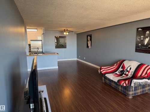 Open-concept interior featuring wood-finish flooring, a breakfast bar, and a ceiling fan - #1304 10160 116 St Nw, Edmonton, AB 