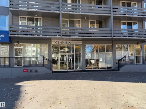 Multi-story facade featuring floor-to-ceiling glass entry doors, expansive storefront windows, private balconies with horizontal railings, and concrete hardscaping - #1304 10160 116 St Nw, Edmonton, AB 