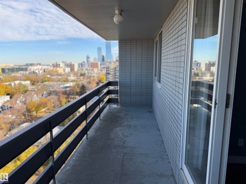 Private balcony featuring a metal railing, brick exterior wall, and concrete flooring, showcasing an urban cityscape - #1304 10160 116 St Nw, Edmonton, AB 