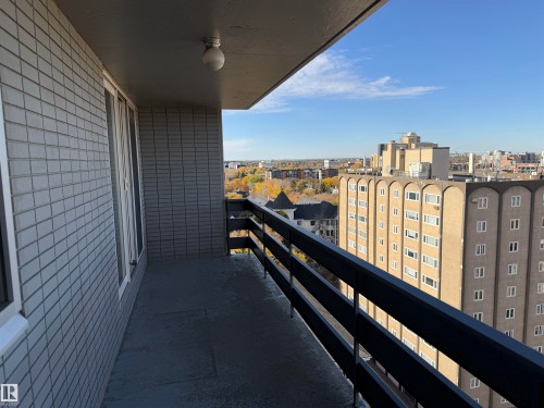 Covered balcony featuring grey brick walls, a flush-mount ceiling light, and black metal railings - #1304 10160 116 St Nw, Edmonton, AB 