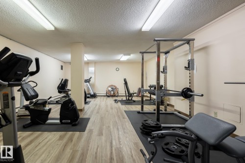Spacious room featuring wood-finish flooring and linear recessed fluorescent lighting - #1304 10160 116 St Nw, Edmonton, AB 