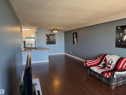 Open-concept living space featuring wood-finish flooring, recessed ceiling lighting, and a kitchen breakfast bar - #1304 10160 116 St Nw, Edmonton, AB 