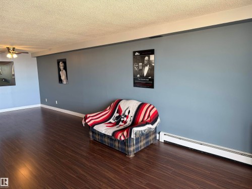 Spacious room featuring wood-finish flooring, painted walls, and a ceiling-mounted light fixture - #1304 10160 116 St Nw, Edmonton, AB 