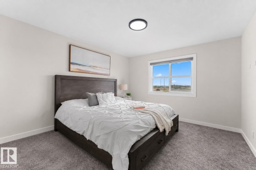 Spacious room featuring neutral wall tones, a large window with white trim, and a flush-mount ceiling light - 1142 Goldfinch Crescent Nw, Edmonton, AB 