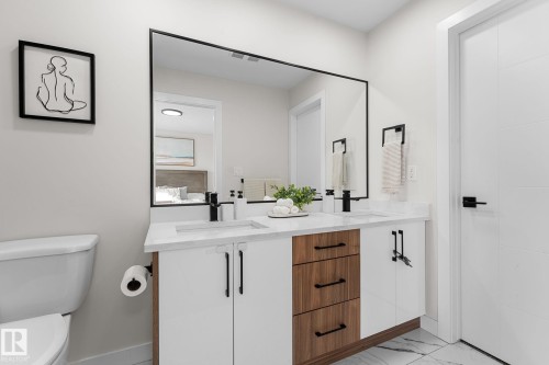 Dual vanity with white countertop, integrated sinks, black fixtures, and a large framed mirror - 1142 Goldfinch Crescent Nw, Edmonton, AB 