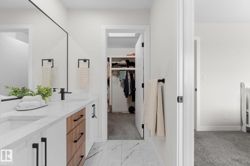 Dual-sink vanity with a white countertop and contrasting wood-tone and white cabinetry - 1142 Goldfinch Crescent Nw, Edmonton, AB 