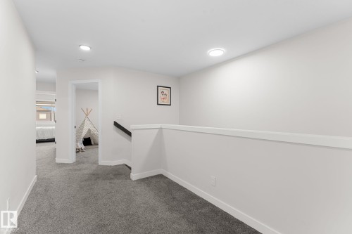 Recessed ceiling lighting illuminates the gray carpeted hallway with white painted walls - 1142 Goldfinch Crescent Nw, Edmonton, AB 