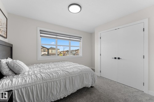 Recessed window with horizontal blinds, flush-mount ceiling light, white double closet doors with matte black hardware, and gray carpet flooring - 1142 Goldfinch Crescent Nw, Edmonton, AB 