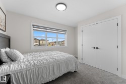 Recessed window with horizontal blinds, flush-mount ceiling light, white double closet doors with matte black hardware, and gray carpet flooring - 