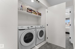 Dedicated laundry area featuring a front-load washer and dryer, integrated shelving, recessed lighting, and tile flooring - 