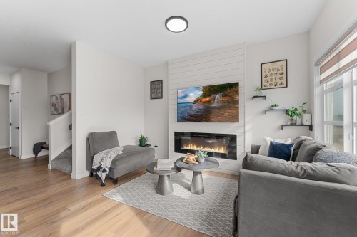 Wood-finish flooring, white walls, and an electric fireplace with shiplap-style surround - 1142 Goldfinch Crescent Nw, Edmonton, AB 