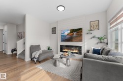 Wood-finish flooring, white walls, and an electric fireplace with shiplap-style surround - 