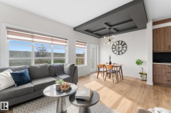 Wood-finish flooring throughout, coffered ceiling with a modern chandelier, large windows with roller shades, and built-in wood-finish cabinetry - 