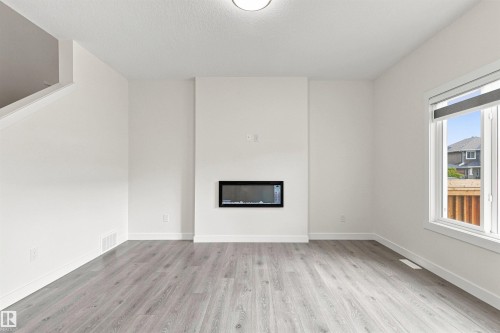 Recessed electric fireplace, light wood-finish flooring, white walls, and a large window with roller shades - 22019 82 Avenue Nw, Edmonton, AB 