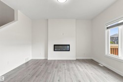Recessed electric fireplace, light wood-finish flooring, white walls, and a large window with roller shades - 