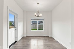 Wood-finish flooring, white walls, and a contemporary chandelier - 