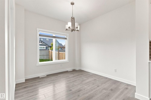 Wood-finish flooring, white walls, modern chandelier, large window with white trim, and white baseboards - 22019 82 Avenue Nw, Edmonton, AB 
