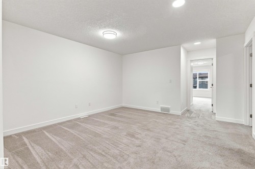 Neutral-toned carpeting, recessed lighting, and a flush-mount ceiling fixture illuminate this expansive room - 22019 82 Avenue Nw, Edmonton, AB 