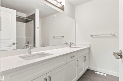 Dual vanity with undermount sinks, white cabinetry, chrome hardware, and a large wall-mounted mirror - 