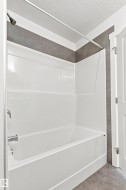 White fiberglass tub and shower combination with a bronze shower head and chrome fixtures - 