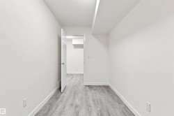 Light wood-finish flooring, white walls, and a white interior door - 