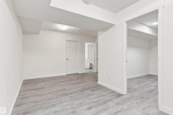 Room featuring wood-finish flooring, white walls, and a ceiling-mounted light fixture - 