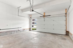 Concrete flooring garage featuring an automatic overhead door opener and a segmented garage door with frosted glass panels - 