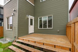 Ground-level wood deck with multi-level steps, green horizontal siding, and multiple windows - 