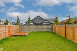 Expansive backyard featuring a lush lawn, wood deck, and perimeter fencing - 