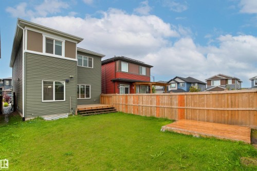 Rear exterior featuring a wood fence, a grassy yard, a multi-level wood deck, and modern horizontal siding - 22019 82 Avenue Nw, Edmonton, AB 
