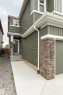 Exterior featuring horizontal siding, vertical siding accents, a prominent stone-clad column, and a concrete walkway - 22019 82 Avenue Nw, Edmonton, AB 