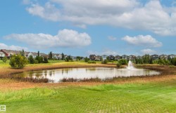 Pond with a decorative fountain, surrounded by natural landscaping and manicured green spaces - 