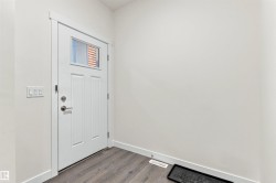 White paneled entry door with frosted glass insert, brushed nickel hardware, and wide white trim - 