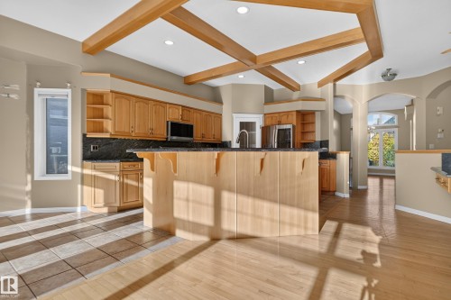 Geometric wood ceiling beams, center island with stone countertops, recessed lighting, and wood-finish flooring - 876 Twin Brooks Close Nw, Edmonton, AB 