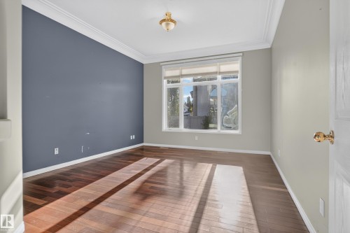 Wood-finish flooring, accent wall, multi-pane window with integrated blinds, crown molding, and ceiling-mounted light fixture - 876 Twin Brooks Close Nw, Edmonton, AB 