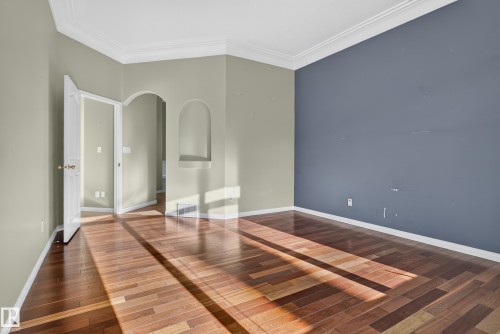 Interior space featuring wood-finish flooring, crown molding, a decorative arched wall niche, and an arched entry - 876 Twin Brooks Close Nw, Edmonton, AB 