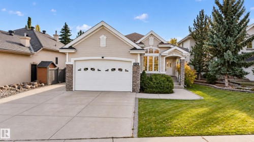 Single-story residence featuring horizontal siding, stone veneer accents, an attached two-car garage, multi-gabled roofline, and a manicured front lawn - 876 Twin Brooks Close Nw, Edmonton, AB 