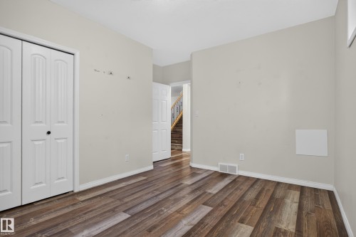Room featuring wood-finish flooring, white six-panel interior doors, and a double-door closet with recessed paneling - 876 Twin Brooks Close Nw, Edmonton, AB 