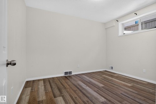 Interior room featuring wood-finish flooring, neutral-toned walls, and a horizontal window - 876 Twin Brooks Close Nw, Edmonton, AB 