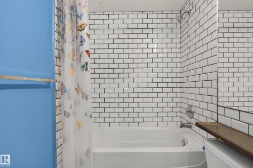 Bathtub surround featuring white subway tile with dark grout, a wall-mounted shower head, and an integrated metal towel bar - 876 Twin Brooks Close Nw, Edmonton, AB 