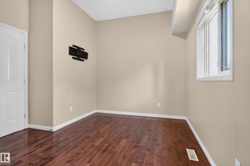 Room featuring wood-finish flooring, neutral wall paint, and a white paneled door - 876 Twin Brooks Close Nw, Edmonton, AB 